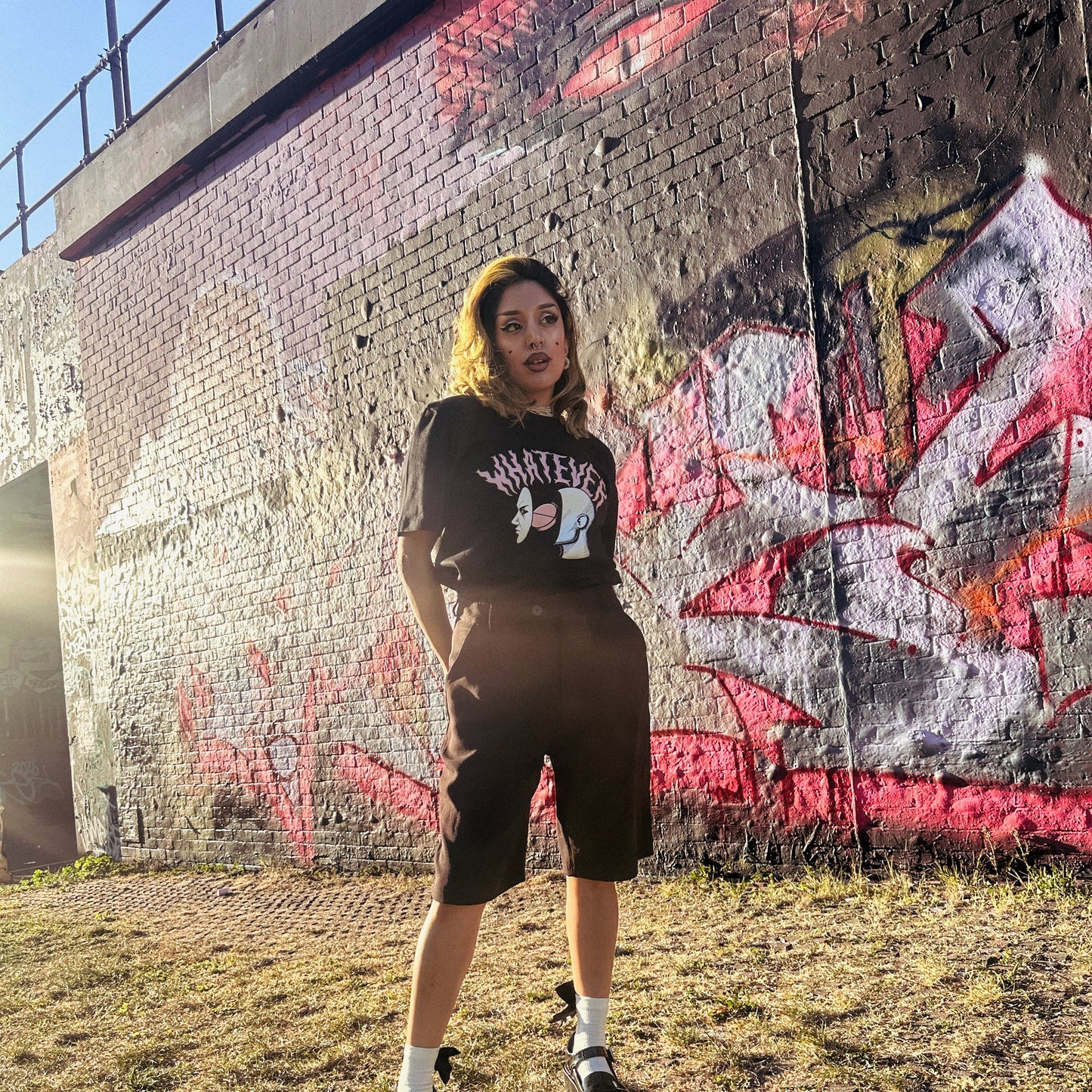 Person standing in front of a graffiti-covered wall