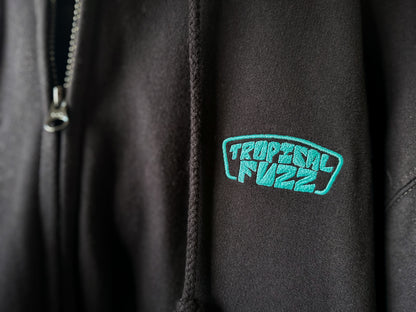 Black zip hoodie with bright green embroidered 'Tropical Fuzz' logo 