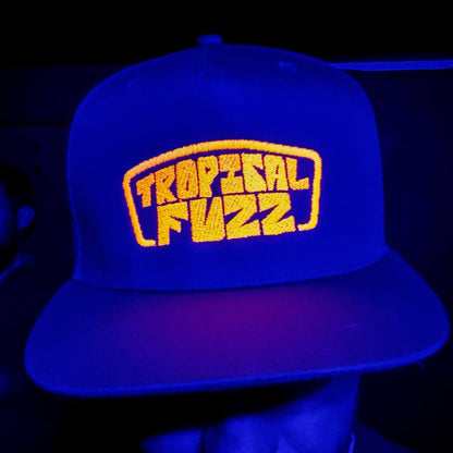 Blue cap with 'Tropical Fuzz' logo under UV light