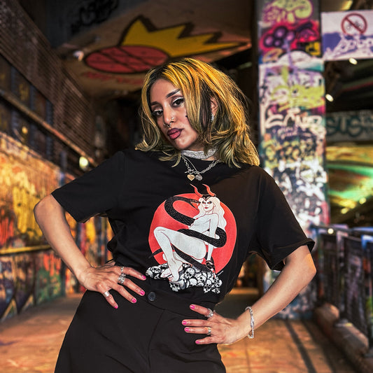 Person wearing a black t-shirt with a graphic design in a graffiti-covered alley.