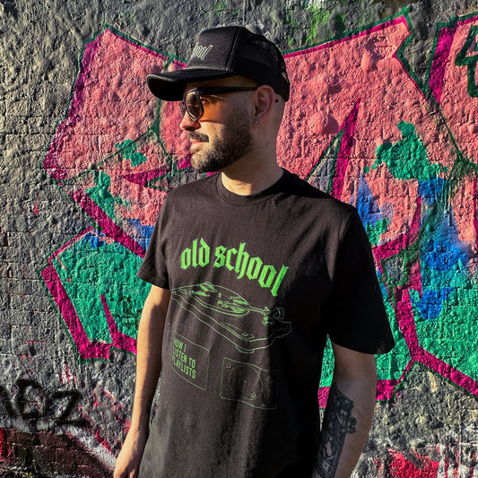 Man wearing a black t-shirt with 'old school' text in front of a colorful graffiti wall.