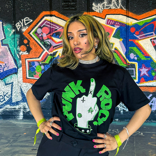 Person wearing a black t-shirt with green and white graphic design in front of a colorful graffiti wall.