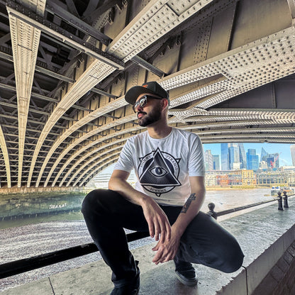 Man sitting on a ledge under a bridge with a cityscape in the background
