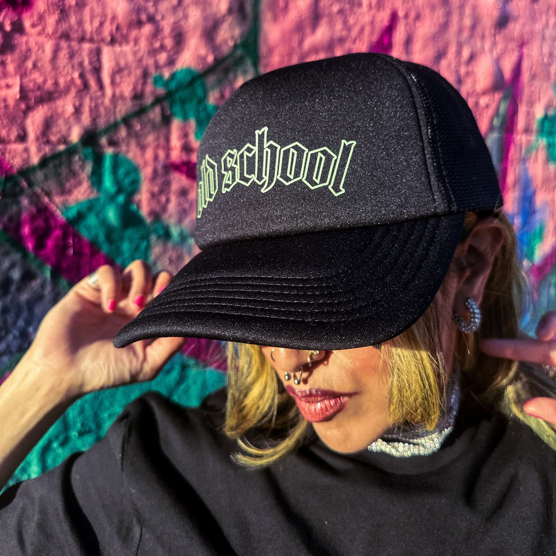 Person wearing a black cap with 'Old School' text against a colorful abstract background